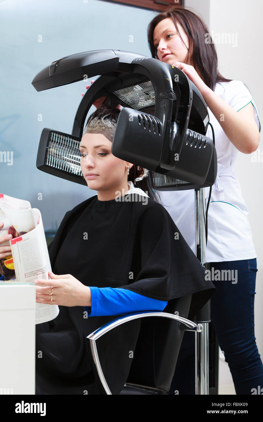 Haidressing salon. Woman dying hair reading magazine. Modern equipment