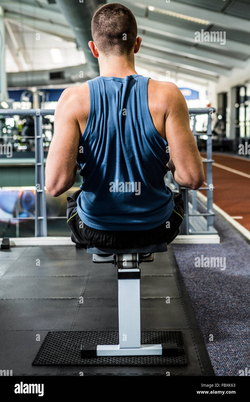 Muscular man using rowing machine Stock Photo