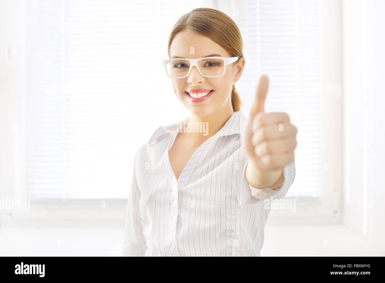 Young business woman showing thumbs up Stock Photo - Alamy