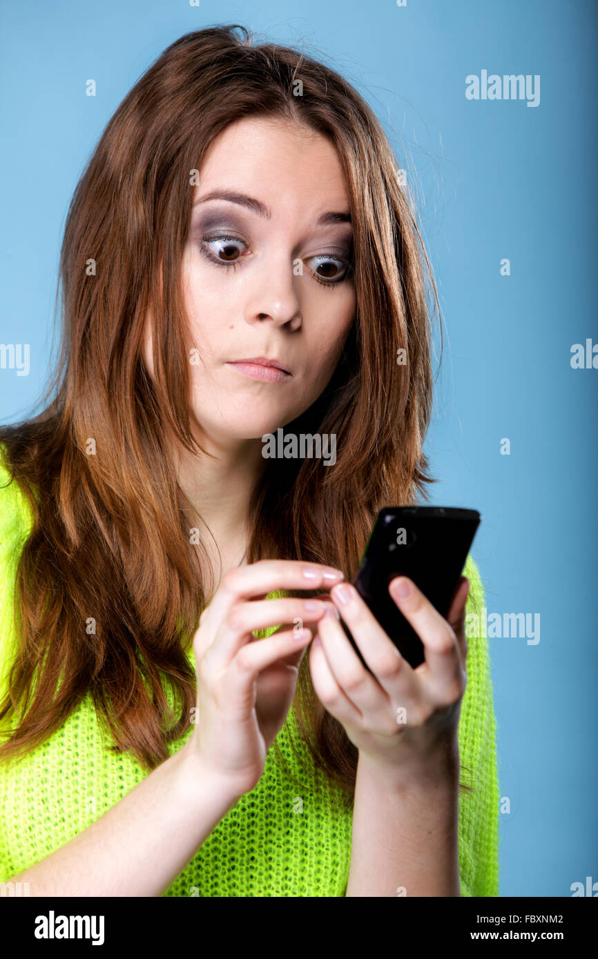 Woman texting while looking surprised on phone Stock Photo - Alamy