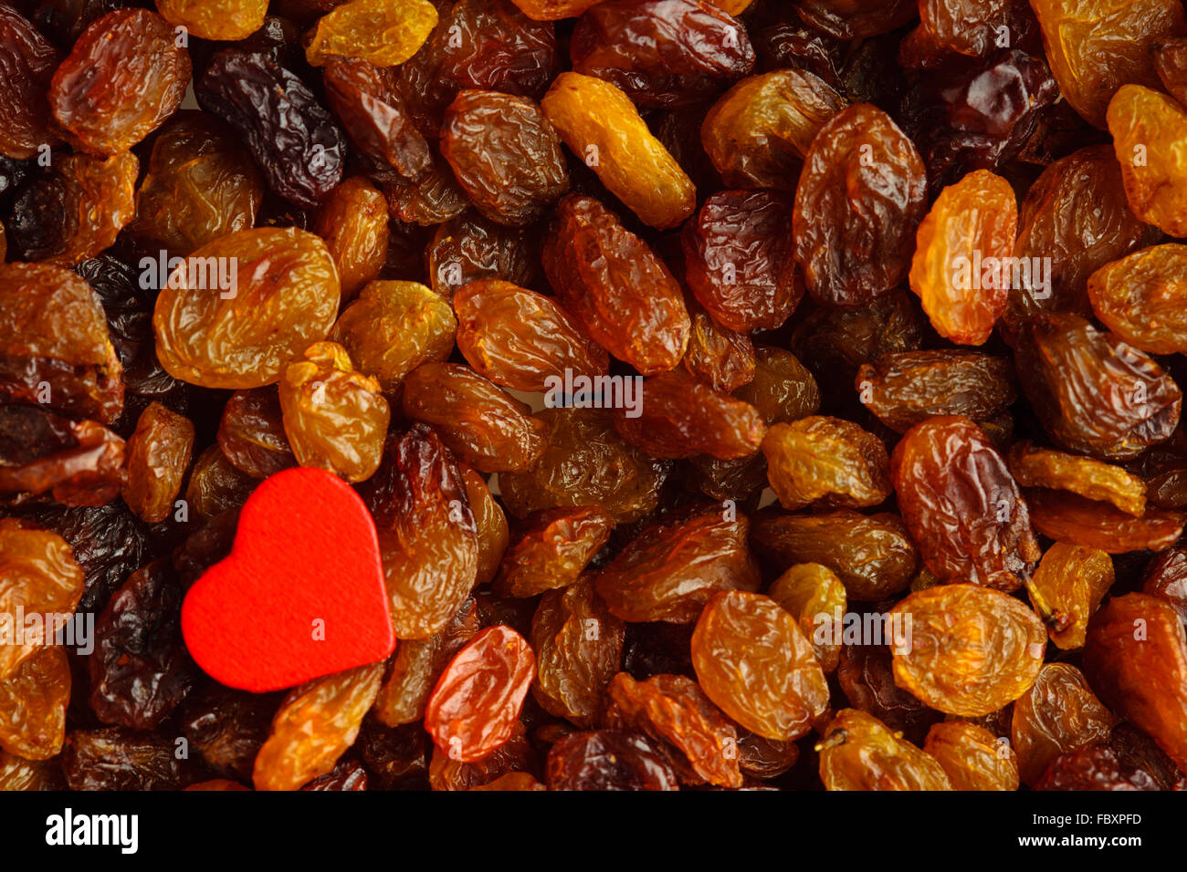 Diet healthy food. Raisin as background texture and red heart Stock