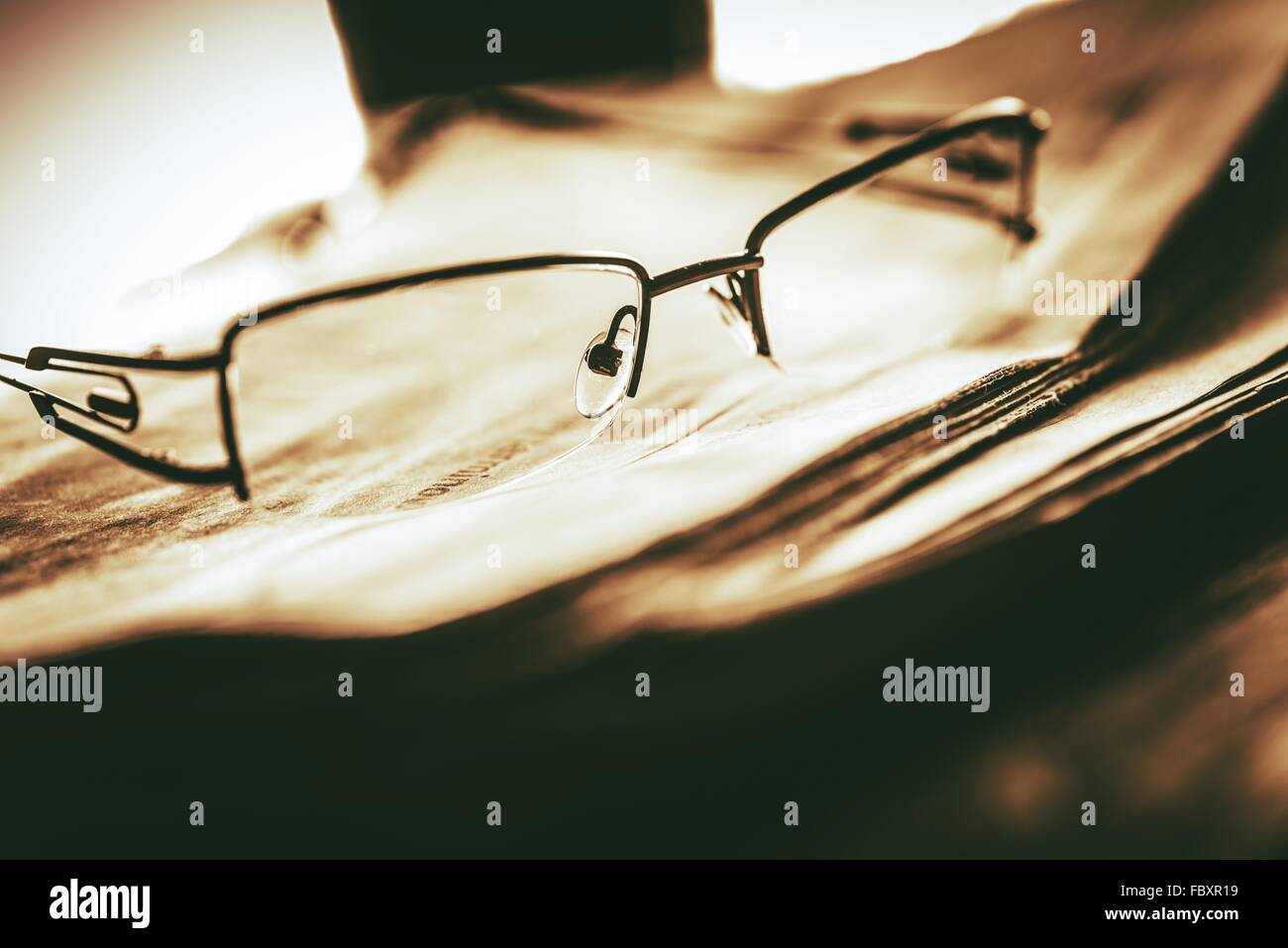Newspapers Reading Concept with Glasses on Pile of Newspapers. Closeup Photo Sepia Color Grading. Stock Photo