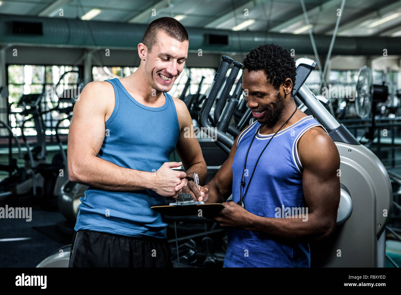 Muscular man discussing performance with trainer Stock Photo - Alamy
