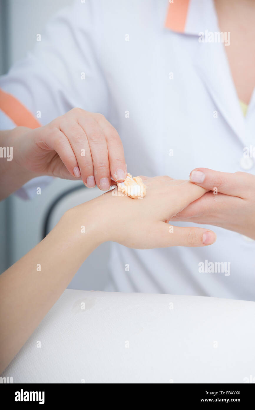 Beautician applying moisturizing cream on client hands. Beauty salon Stock Photo