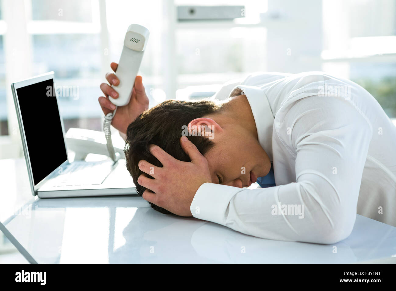 Overwhelmed asian businessman answering the phone Stock Photo