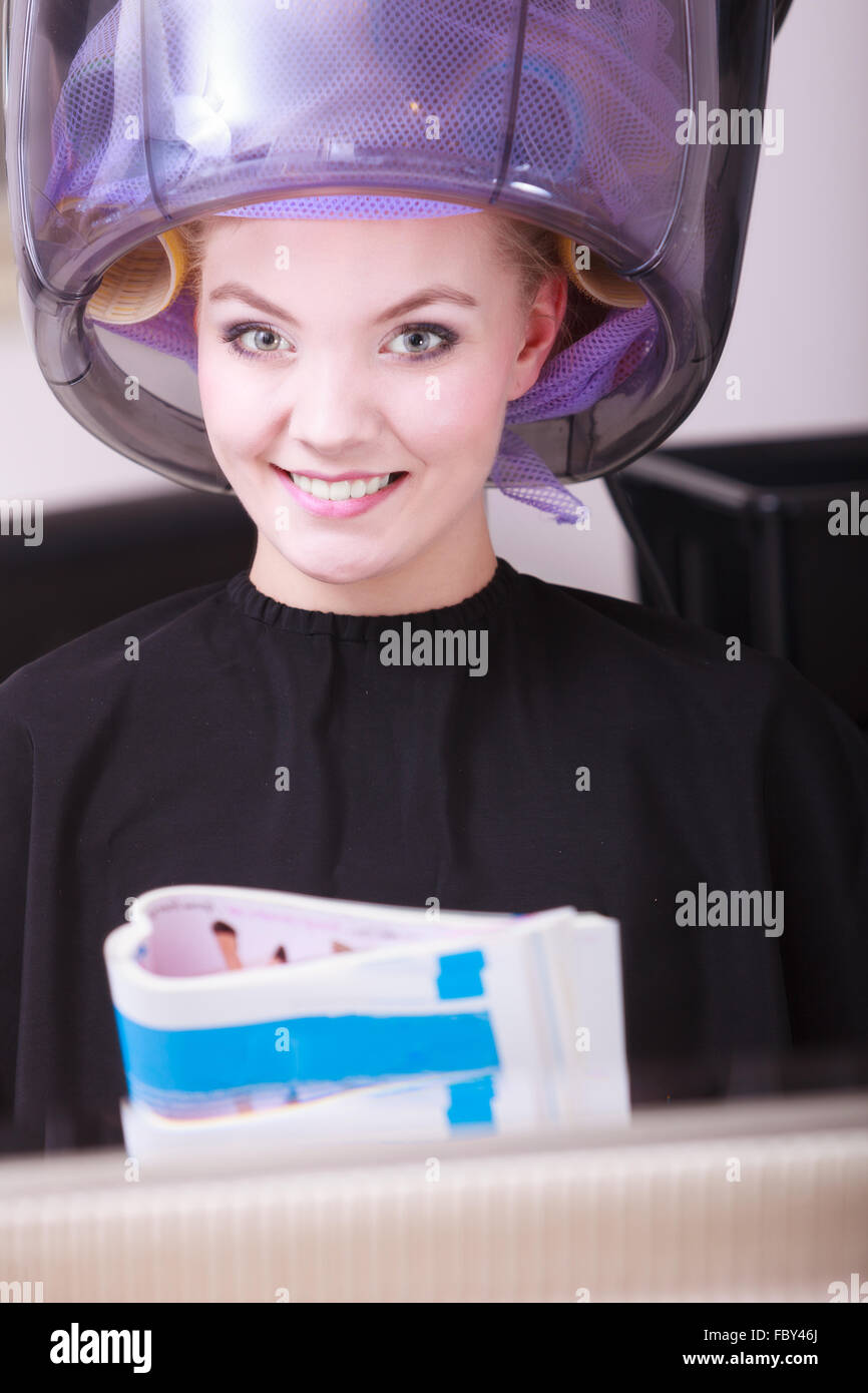 Woman hair rollers curlers reading magazine hairdryer beauty salon