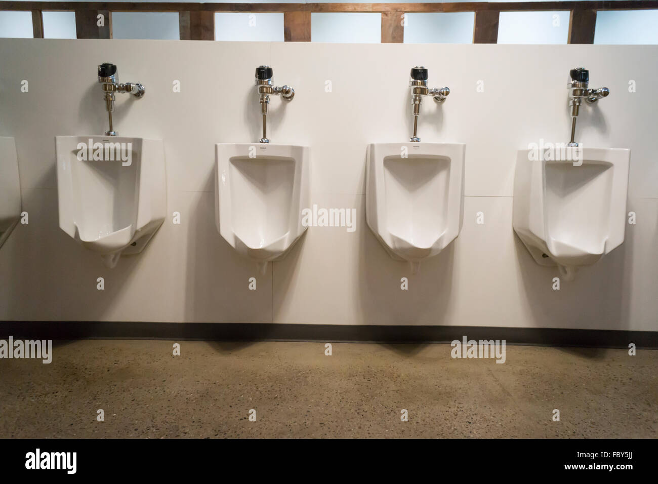 A long line of urinals awaits a multitude of men in a large restroom in