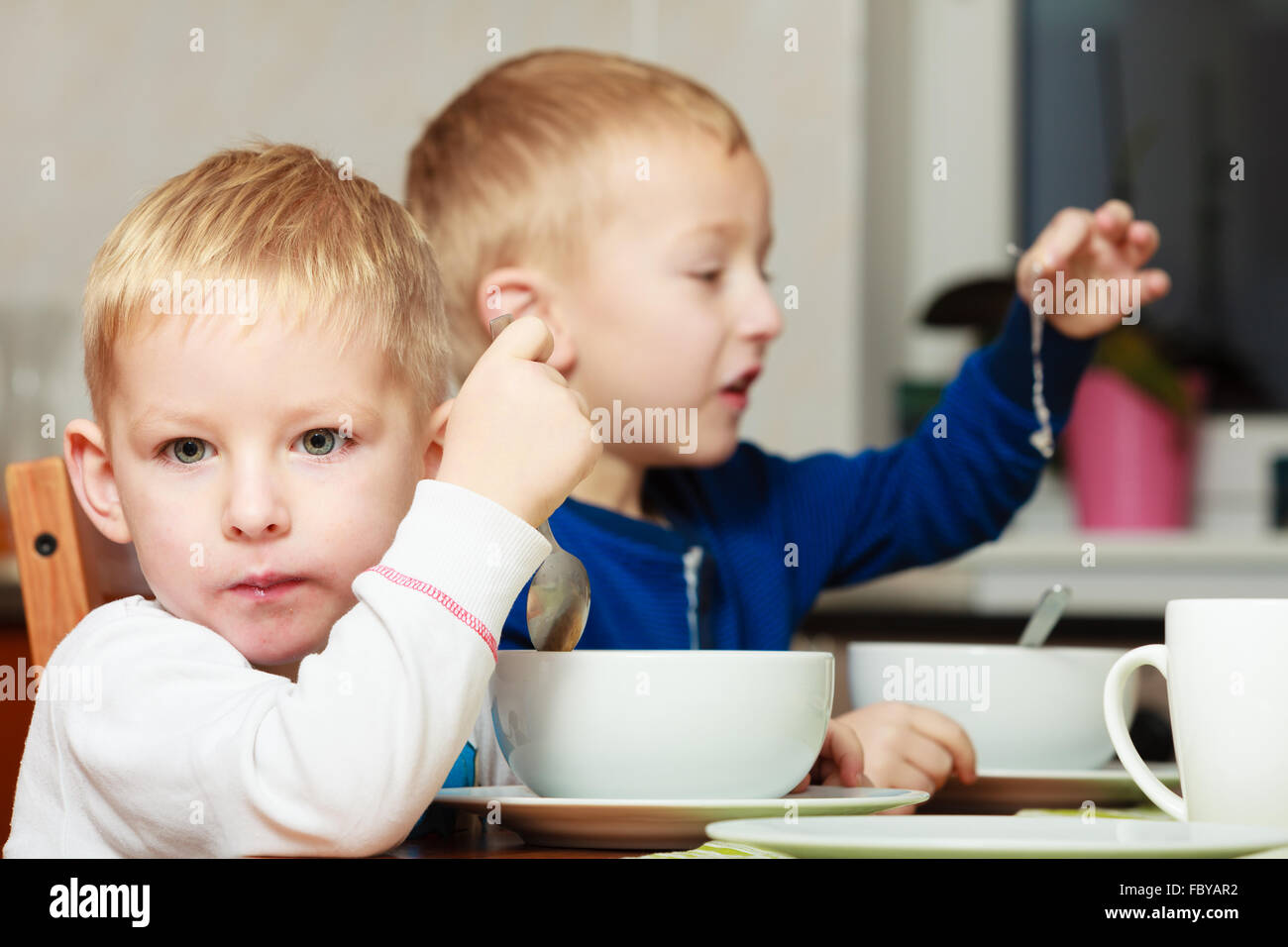Boys kids children eating corn flakes breakfast meal at the table Stock