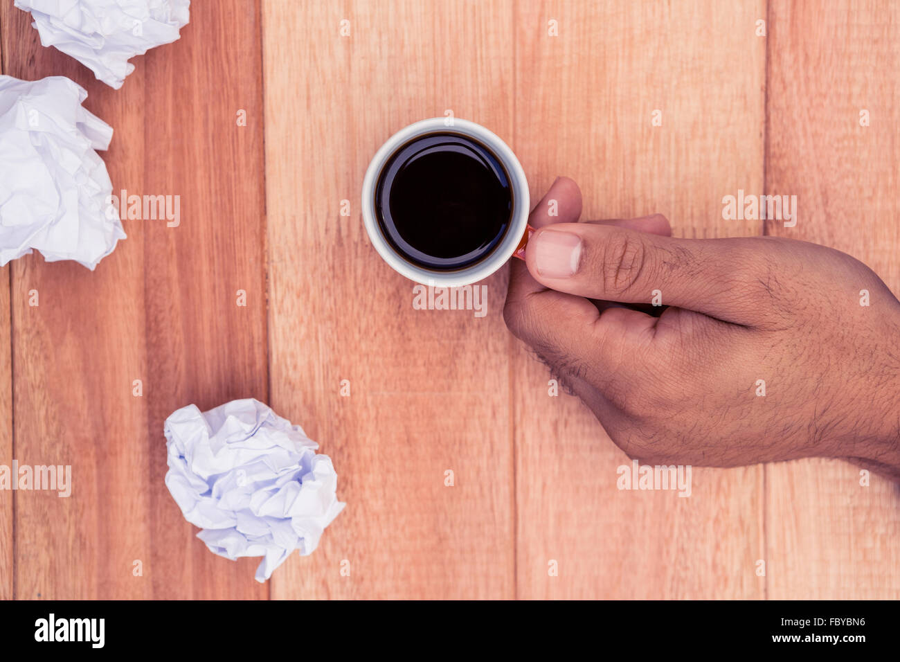 Hand holding coffee cup by crumbled paper on desk Stock Photo - Alamy