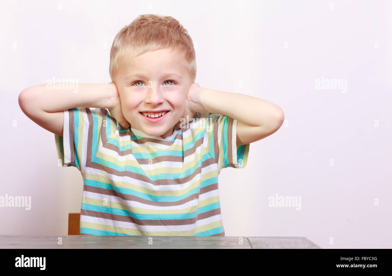 Portrait of blond boy child kid covering ears at the table Stock Photo