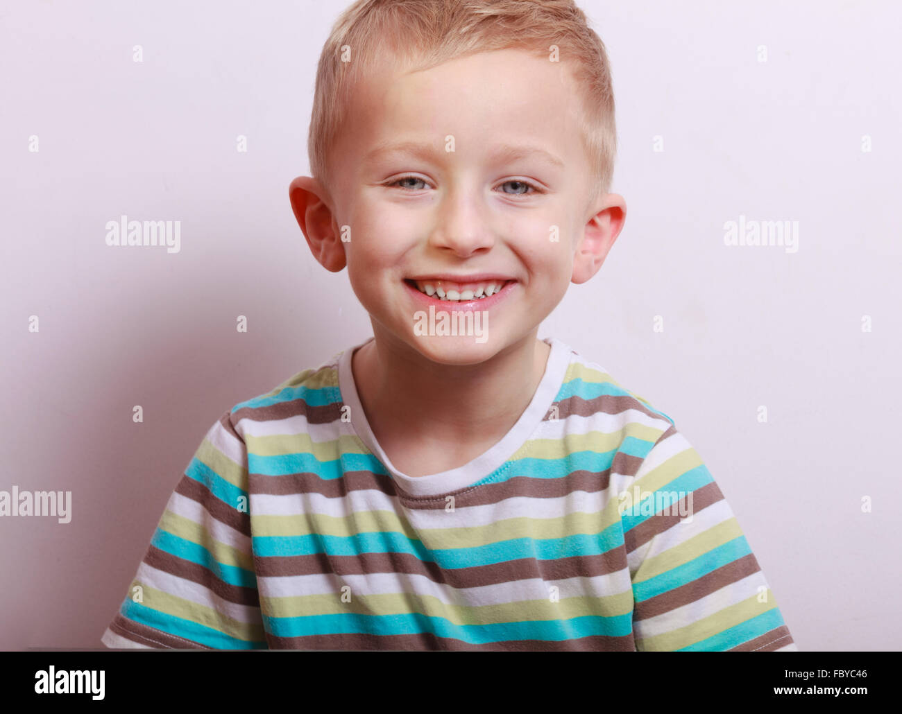 Portrait of happy laughing blond boy child kid at the table Stock Photo