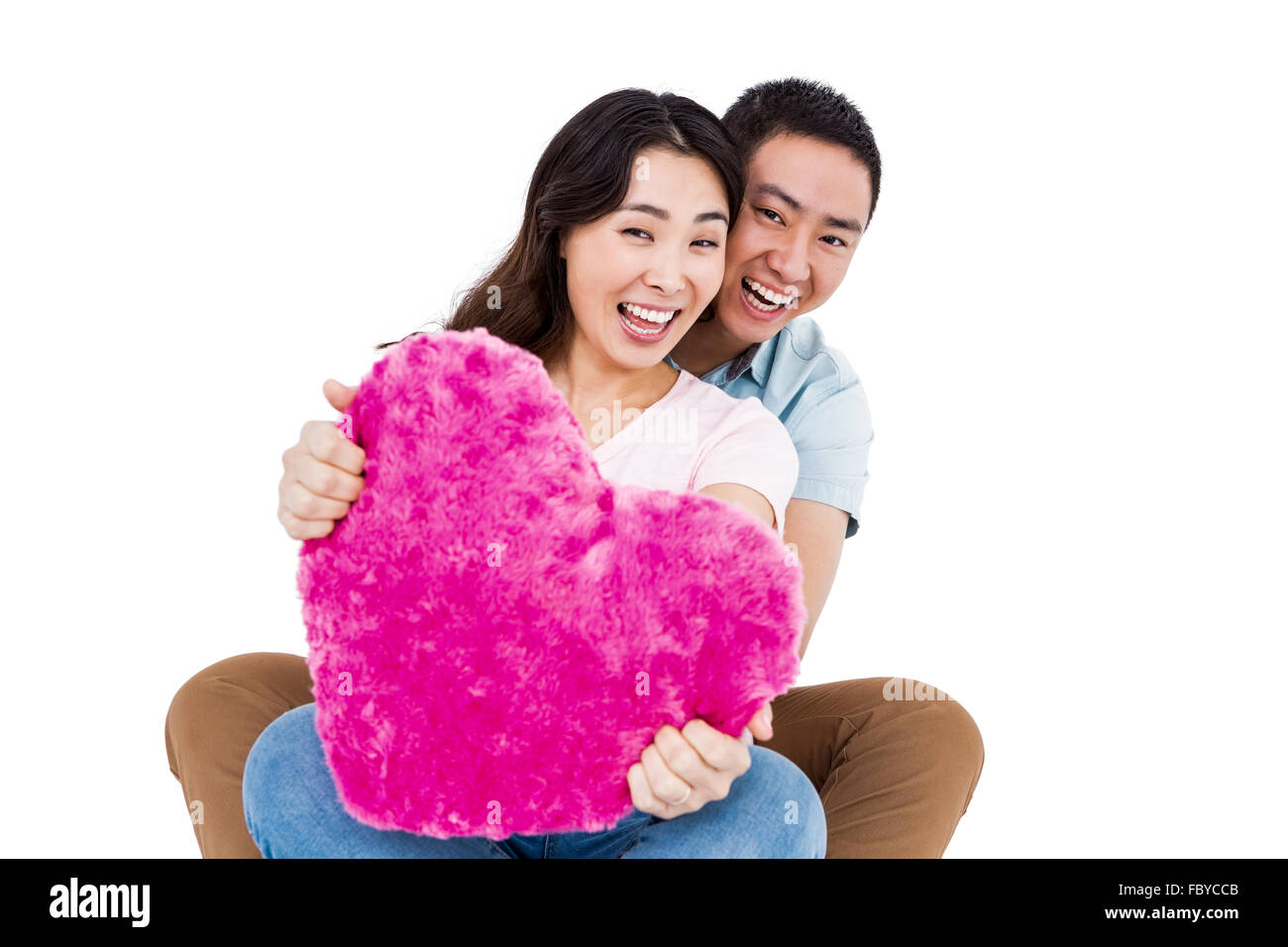 Portrait of cheerful young couple with heart shape pillow Stock Photo ...