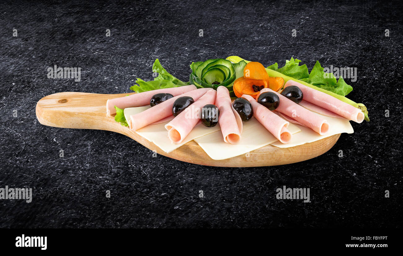Sliced ham salami decorated on wooden board with olives, tomato and lettuce and clipping path Stock Photo