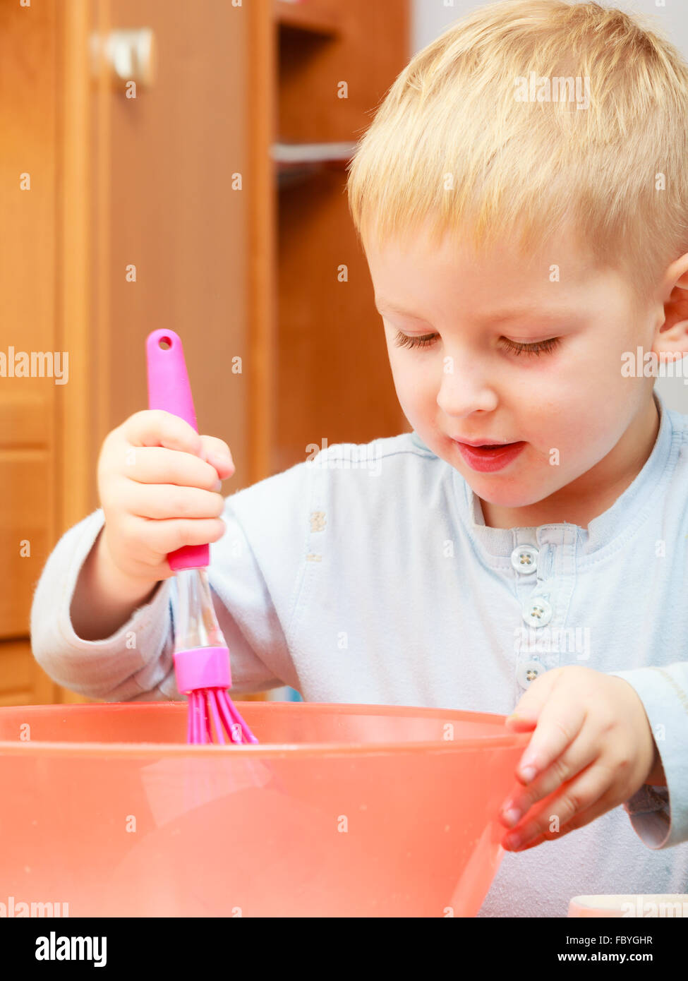 Boy kid baking cake. Child beating dough with wire whisk. Kitchen Stock
