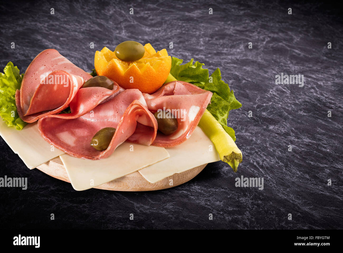 Mortadella slice and vegetables on wooden board with clipping path Stock Photo