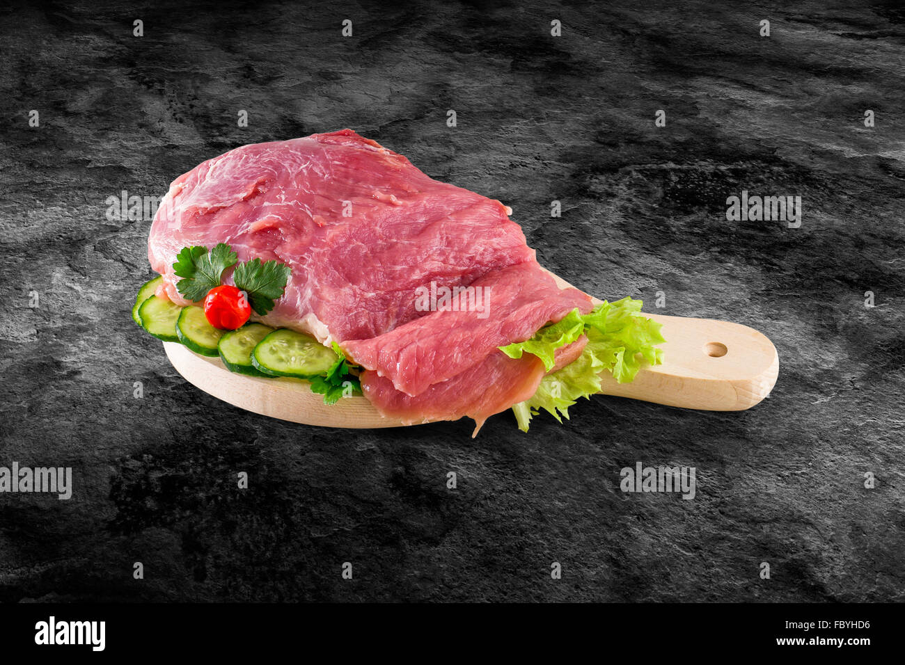 Fresh raw pork ham meat decorated with vegetables on kitchen table plus clipping path Stock Photo