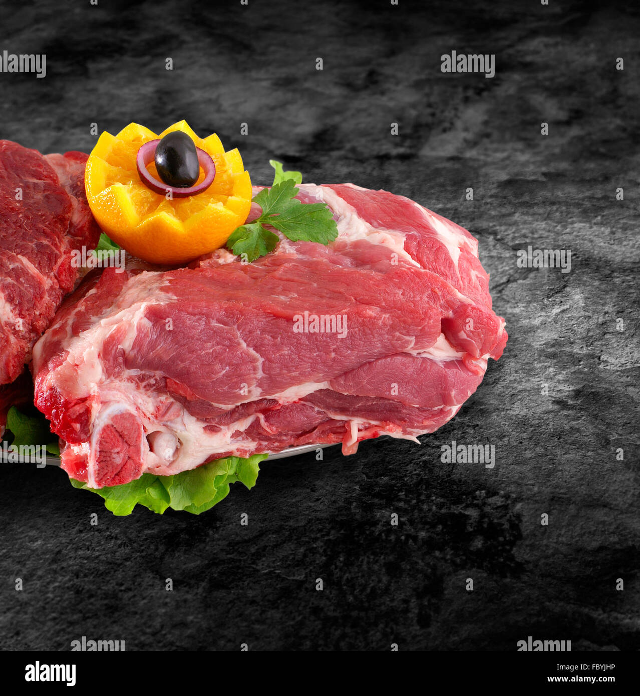Fresh raw pork neck meat decorated with vegetables on kitchen table plus clipping path Stock Photo