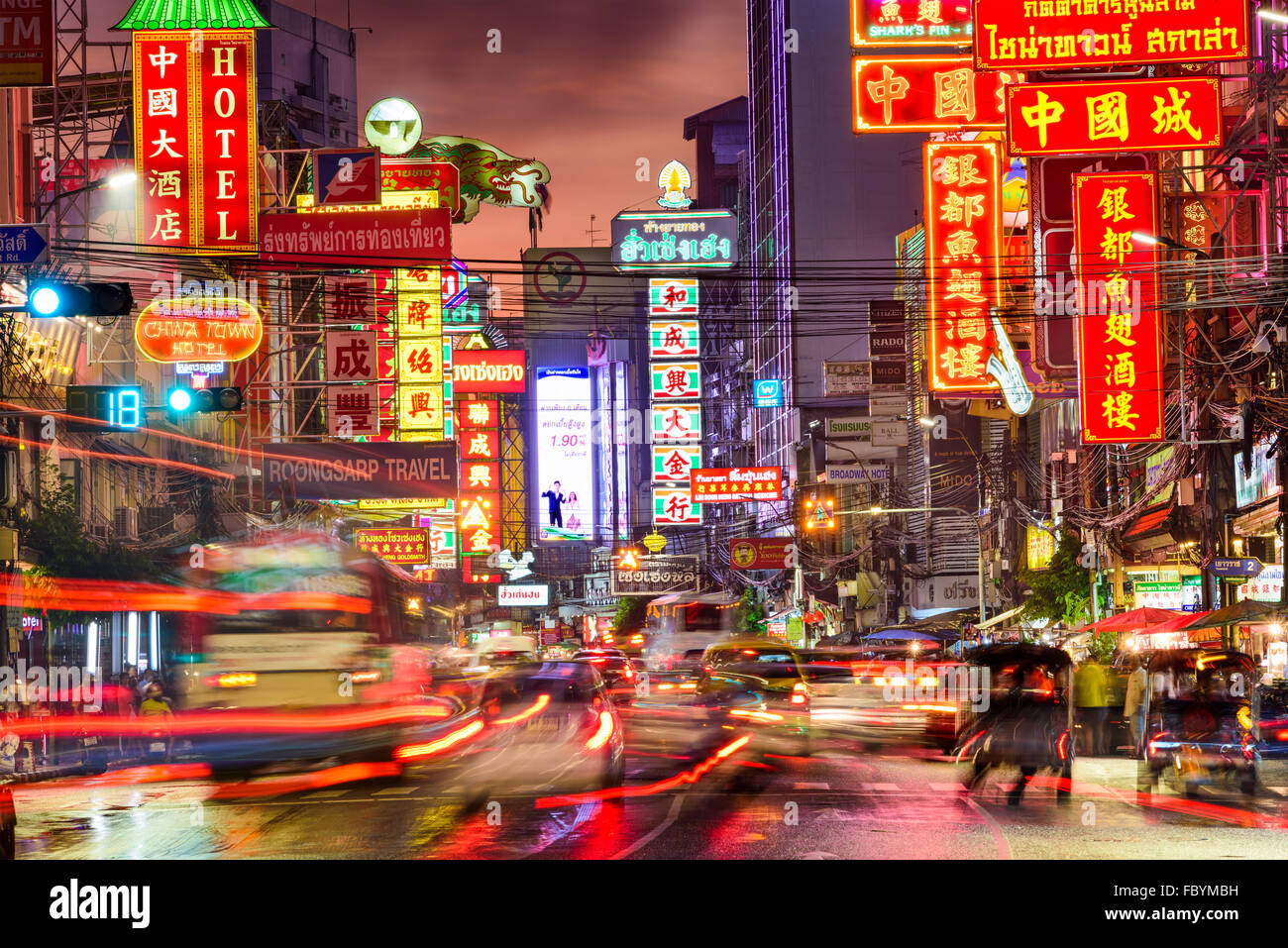 Traffic on Yaowarat Road passes below lit signs in the Chinatown district at dusk in Bangkok, Thailand. Stock Photo