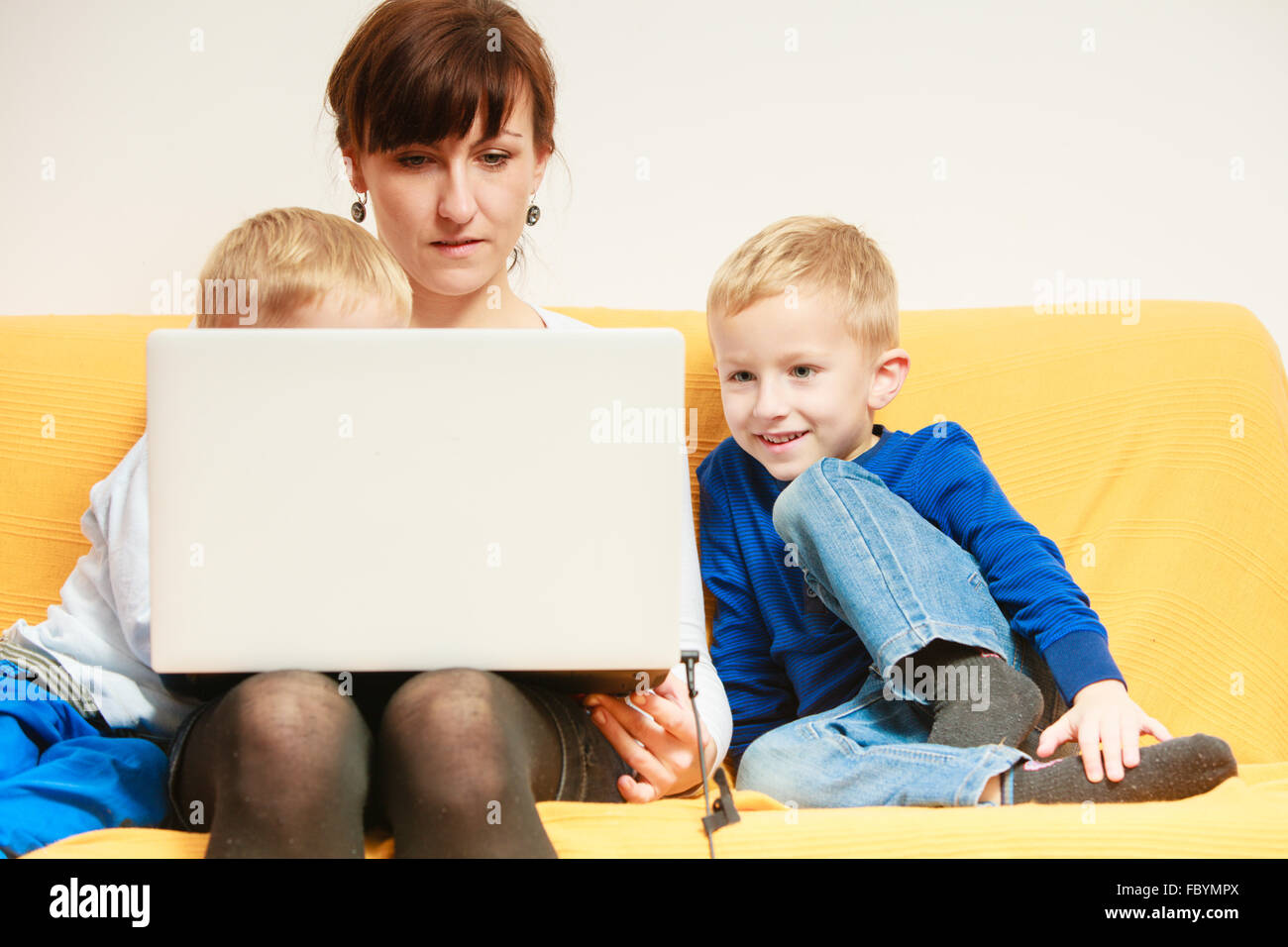 Happy family. Mother and sons using laptop sitting on sofa at home Stock Photo