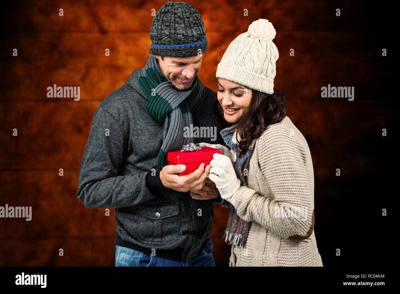 Composite image of festive couple exchanging a gift Stock Photo
