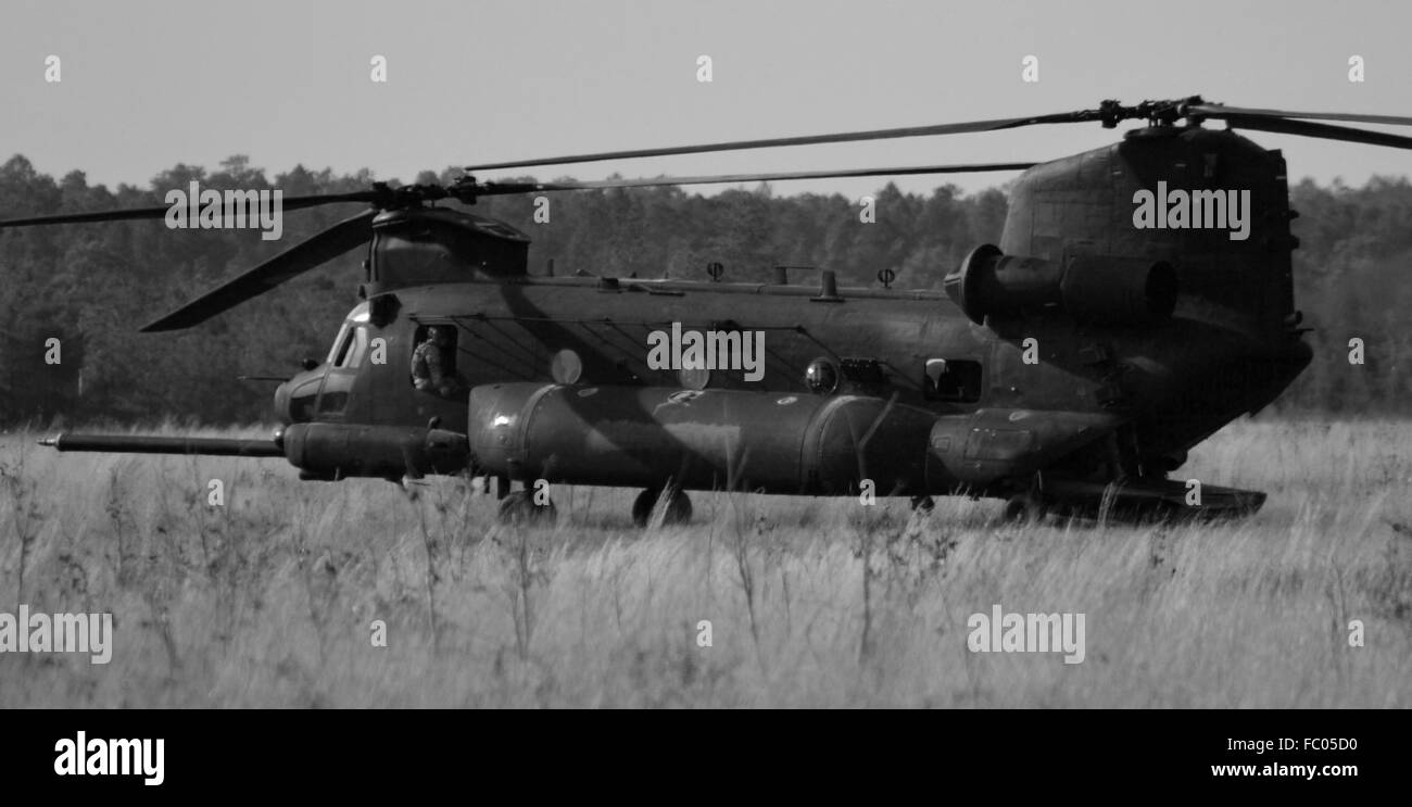 A black special forces CH-47 Chinook assigned to the U.S. Army Nightstalkers lands in a field. Stock Photo