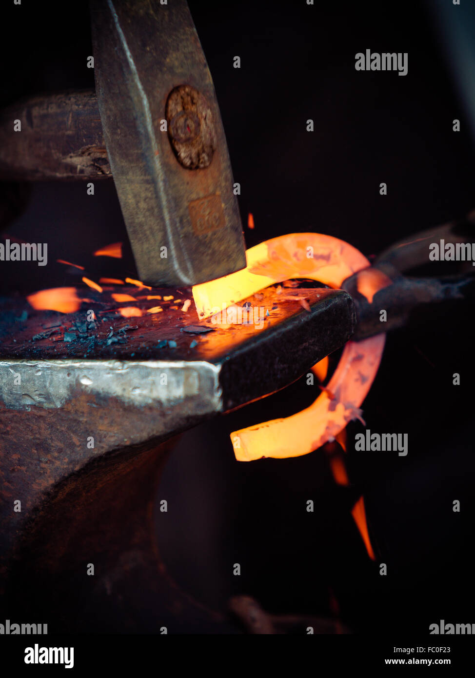 Hammering glowing steel - to strike while the iron is hot. Stock Photo