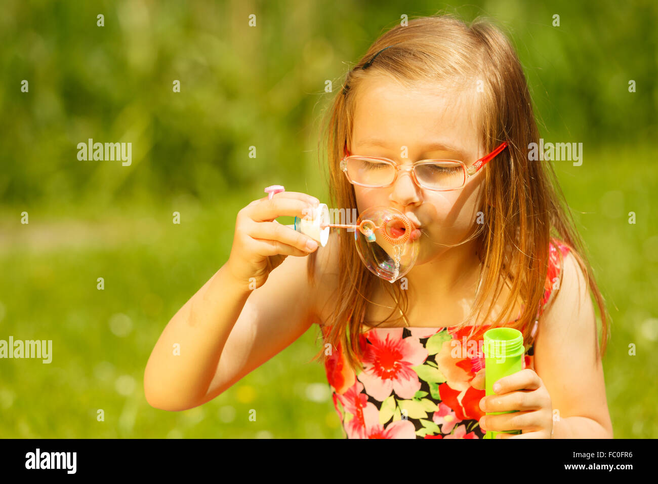 Little girl having fun blowing soap bubbles in park Stock Photo - Alamy