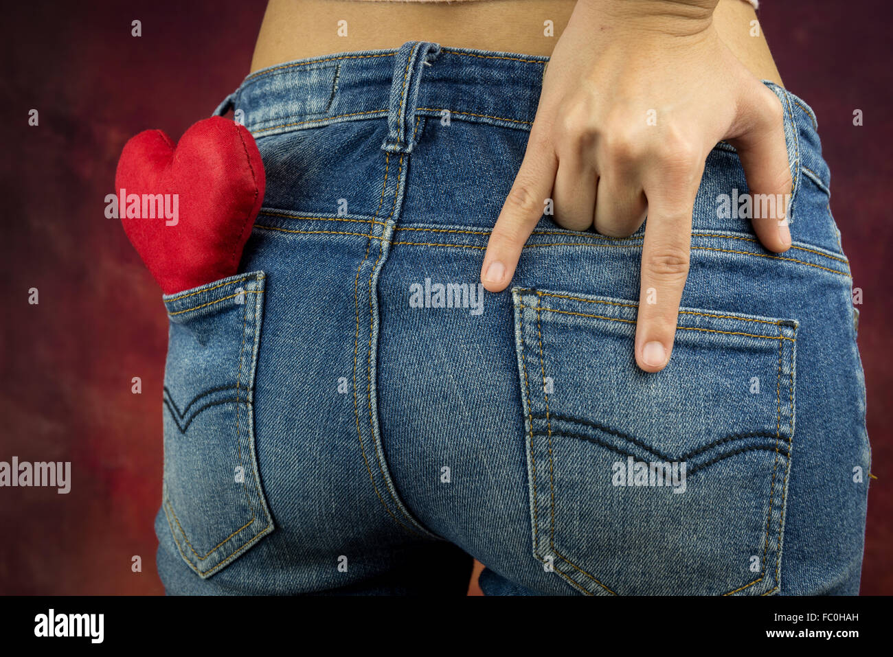 red heart and finger gesture of love by woman shot from her back of the hip, valentine's concept Stock Photo