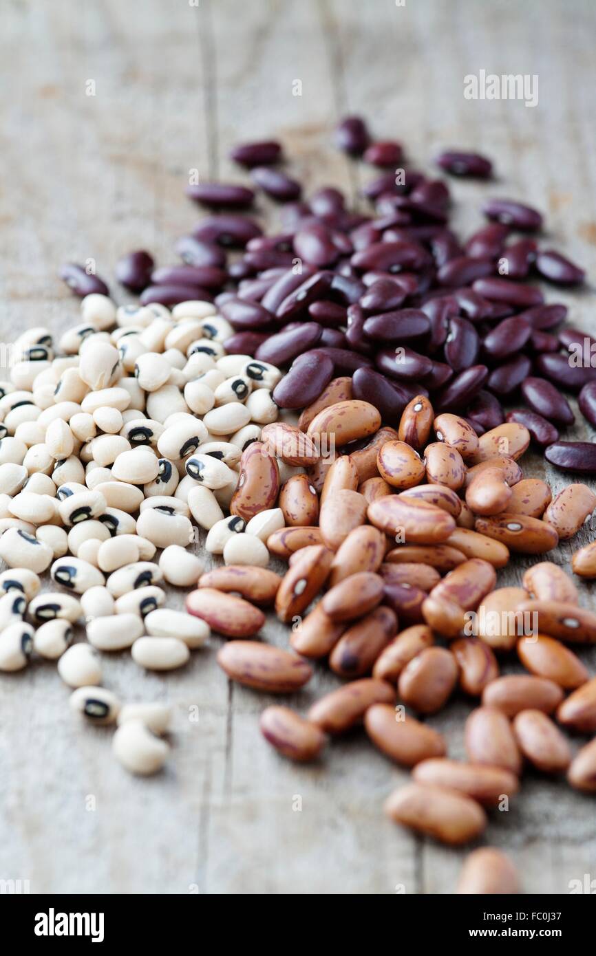 Red kidney beans, black eyed beans and pinto beans on a wood table