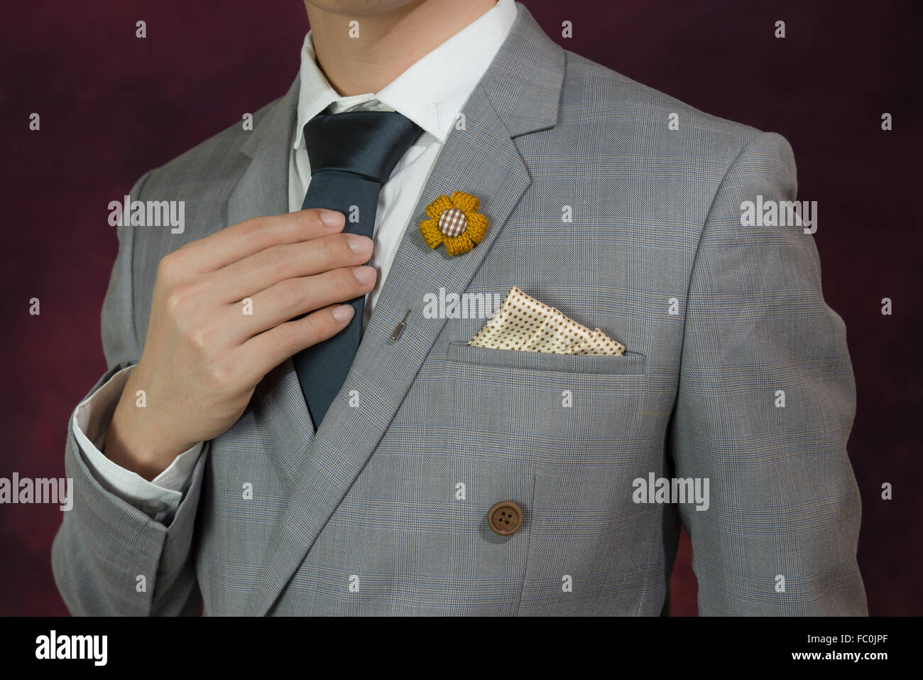 Man in grey suit, plaid texture, blue necktie, flower brooch, and dot pattern handkerchief, close up Stock Photo