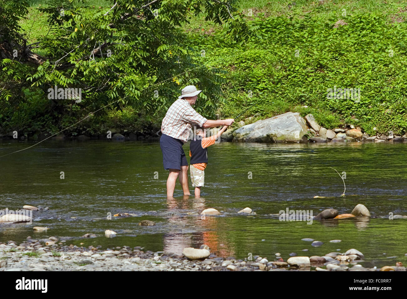 Teaching a young fisherman how to fly fish on a stream in the Smoky Mountains,  near Cherokee, North Carolina, USA. Stock Photo