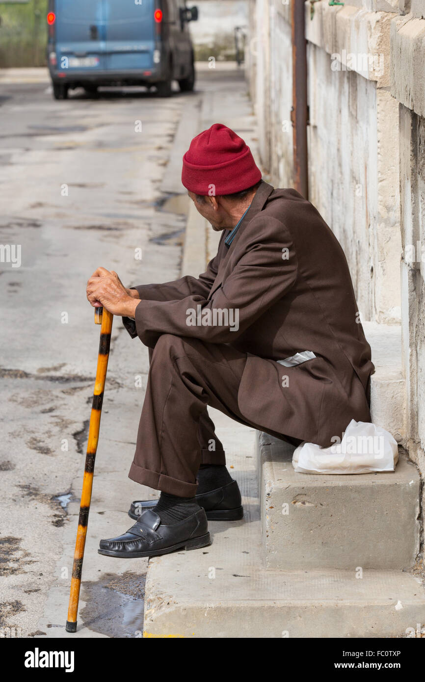 old man sitting in front of a house Stock Photo