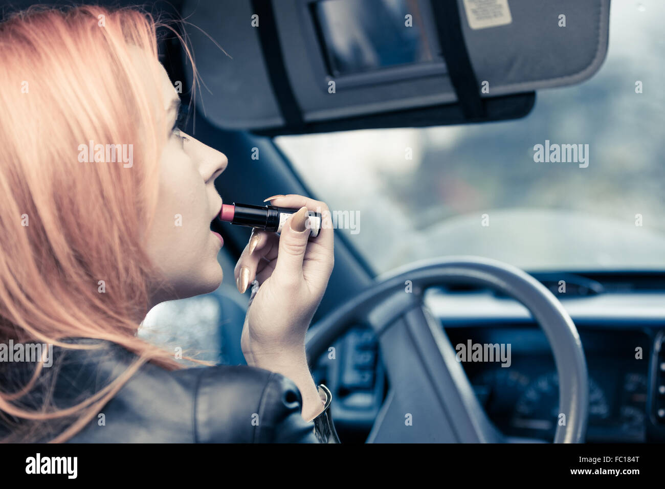 girl painting her lips doing make up while driving the car. Stock Photo