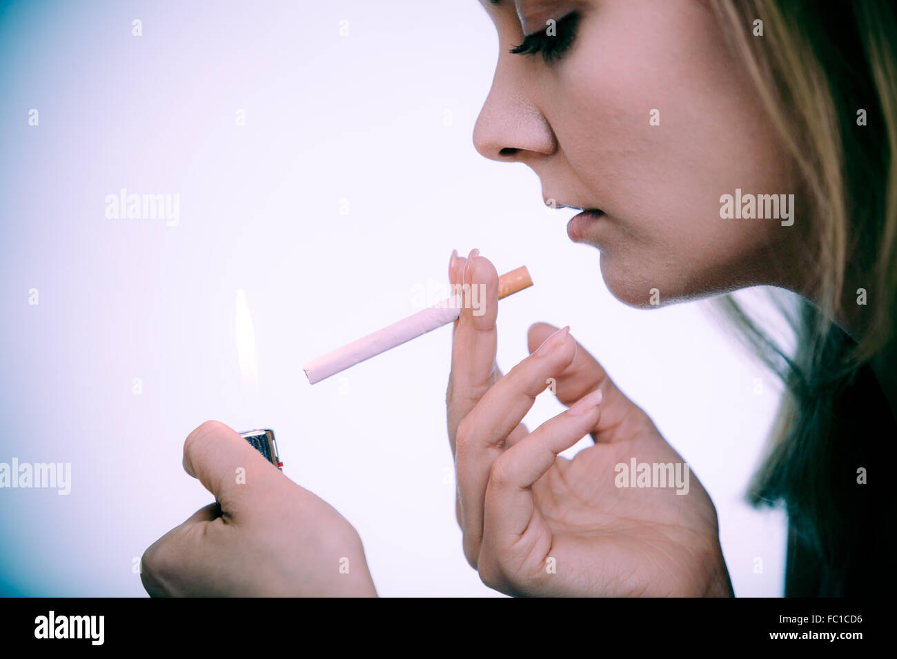 Young woman with lighter lighting up cigarette. Girl smoking. Stock Photo