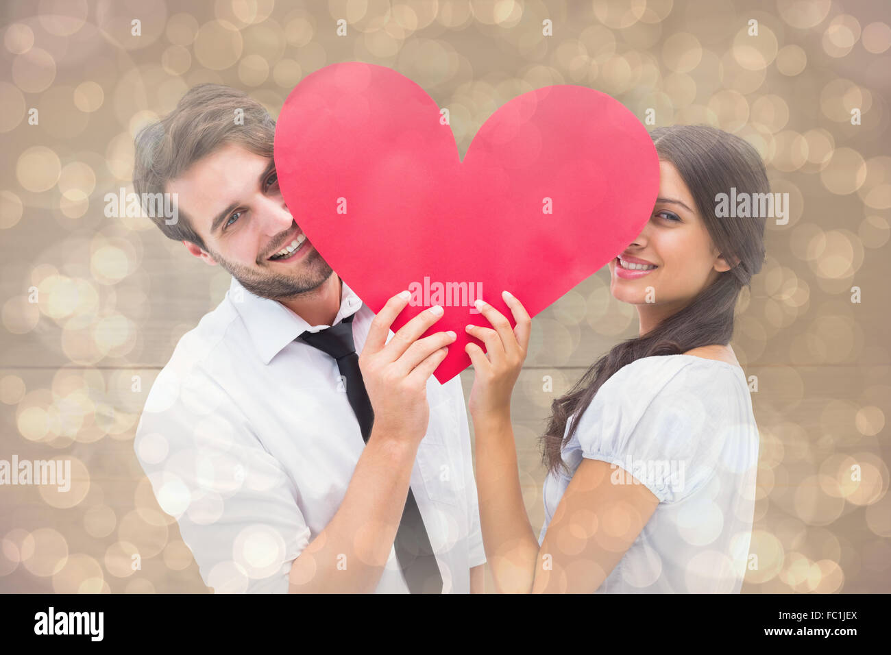 Composite image of couple smiling at camera holding a heart Stock Photo