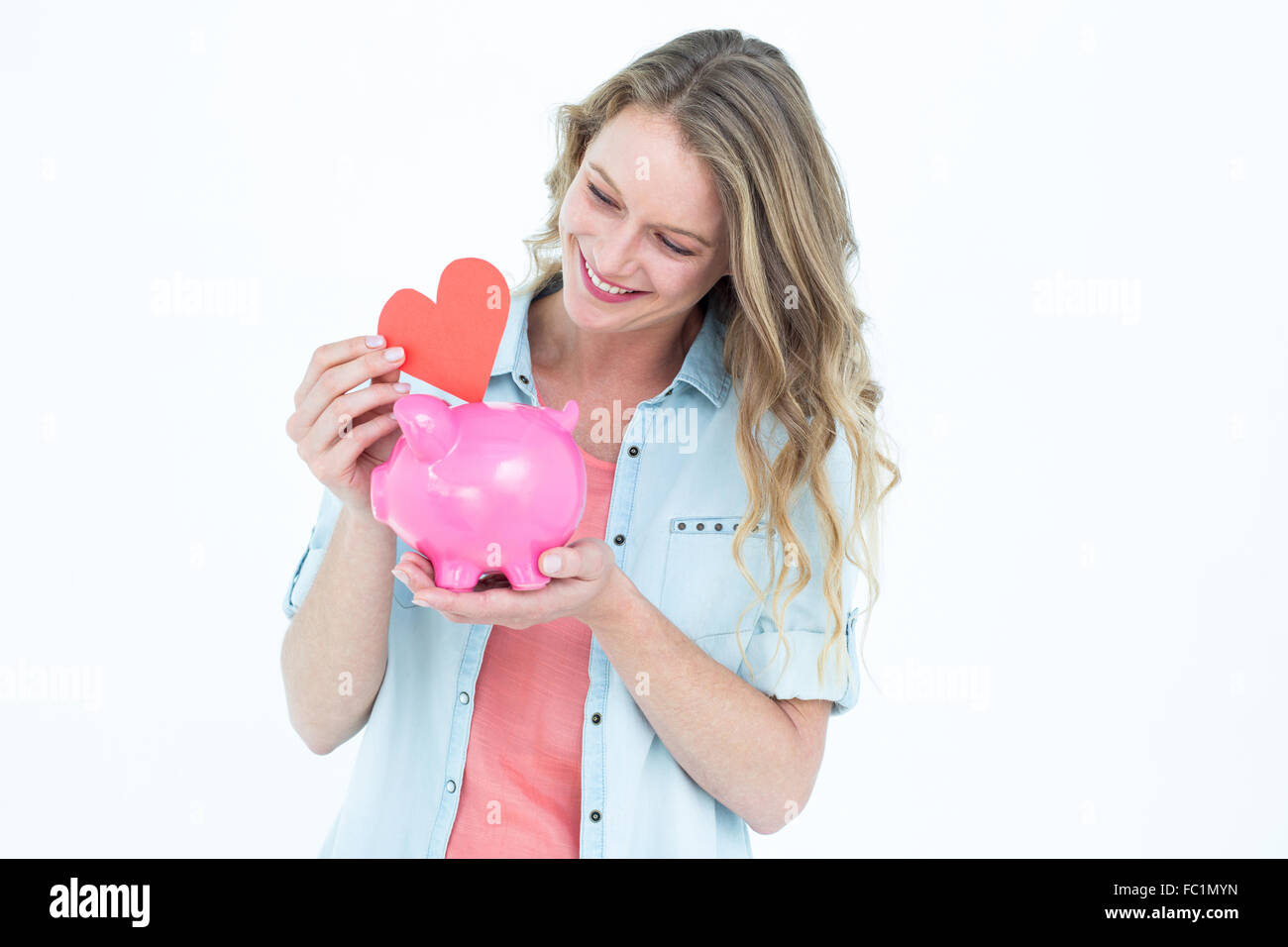 Smiling woman holding piggy bank and red heart Stock Photo - Alamy