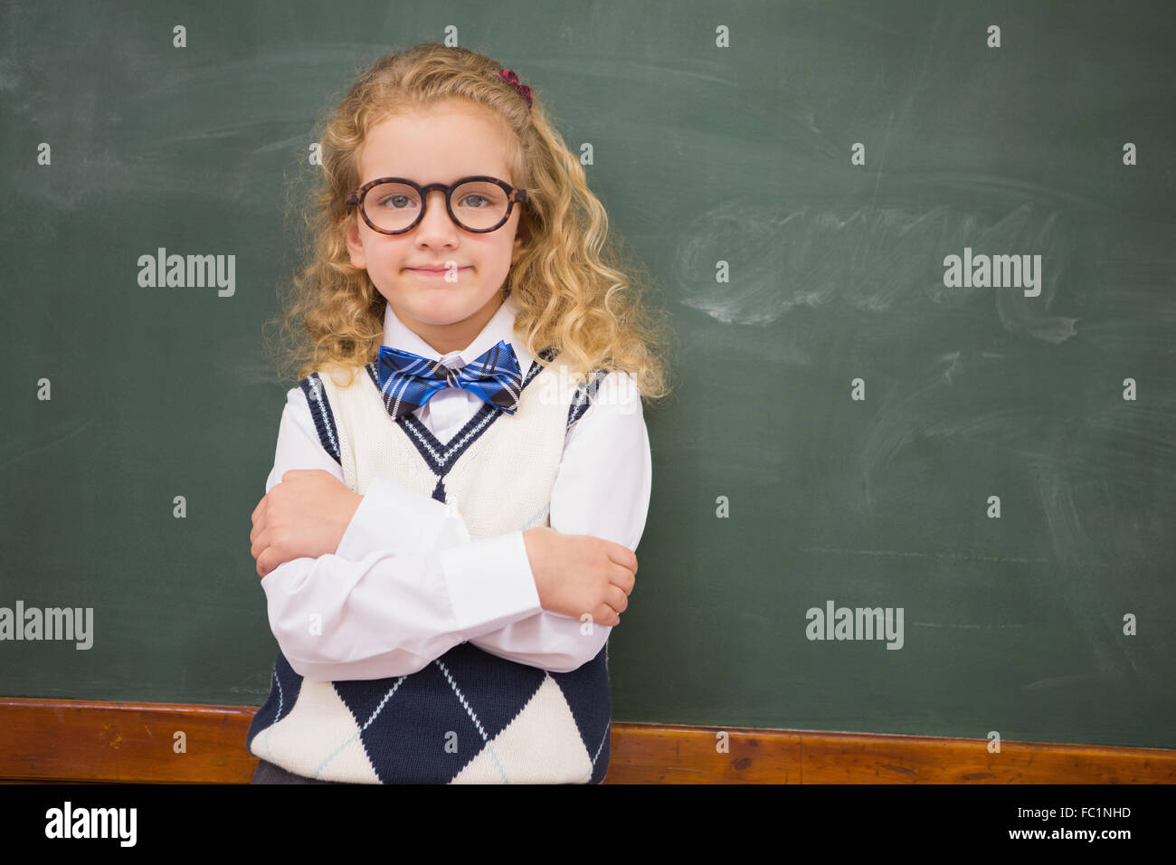 Perplex pupil looking at camera with arms crossed Stock Photo