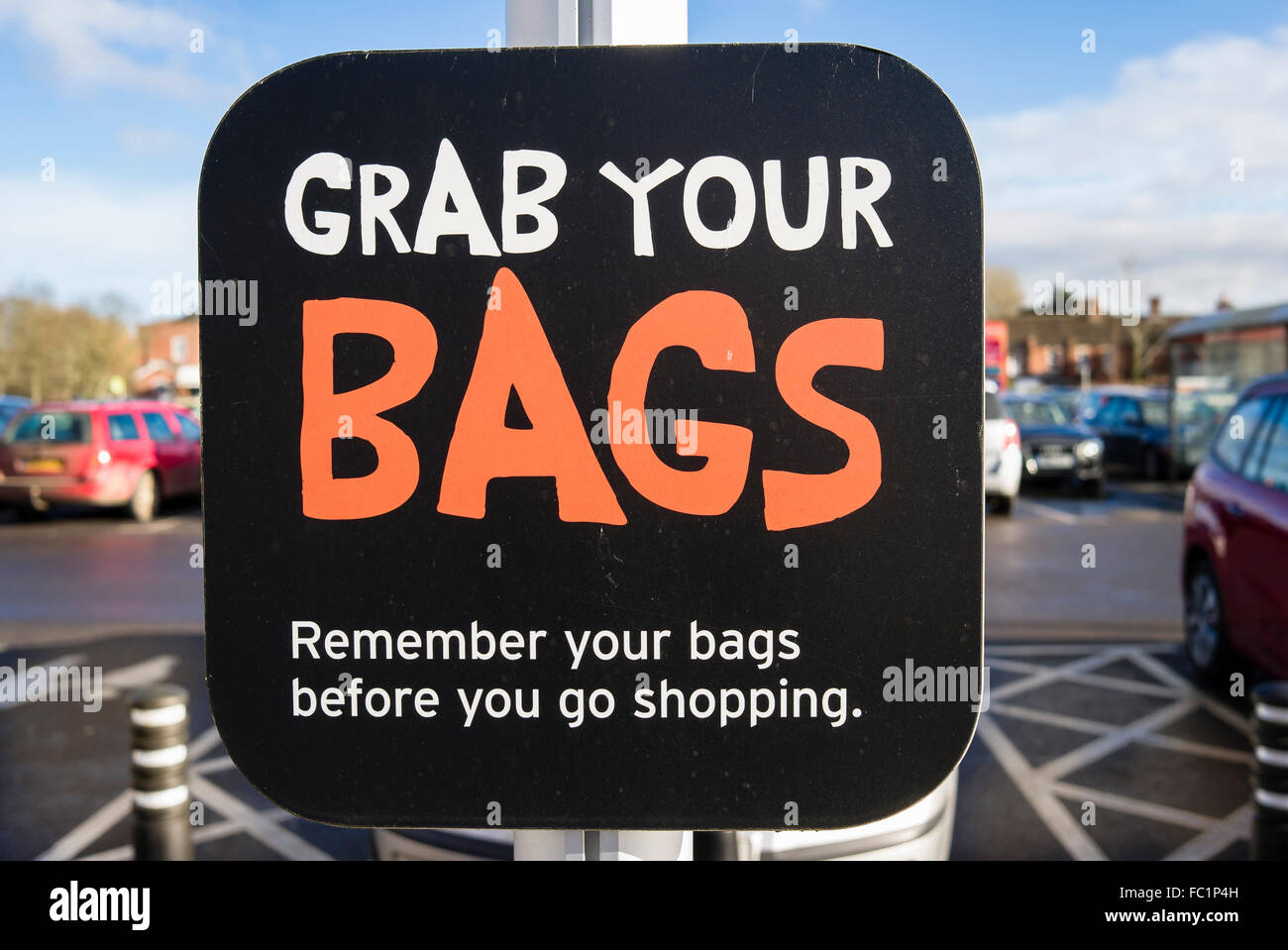 Sign in supermarket carpark GRAB YOUR BAGS serving as a reminder to shoppers that short life plastic bags cost money Stock Photo