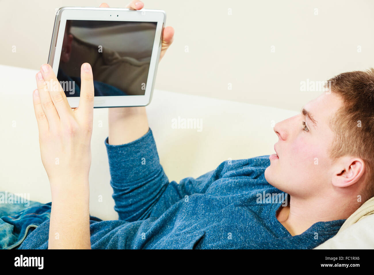 Young man with digital tablet laying on couch Stock Photo