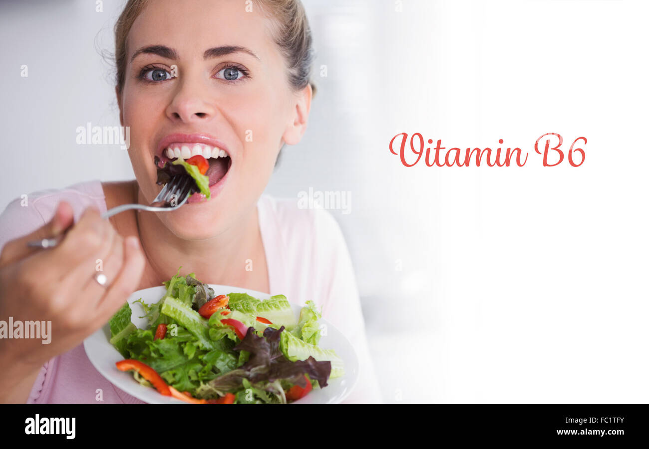 Vitamin b6 against casual blonde posing while eating salad Stock Photo