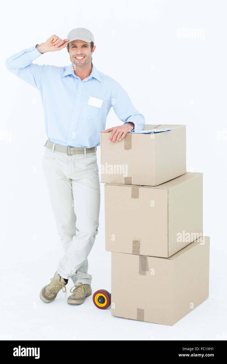 Happy delivery man leaning on stacked cardboard boxes Stock Photo