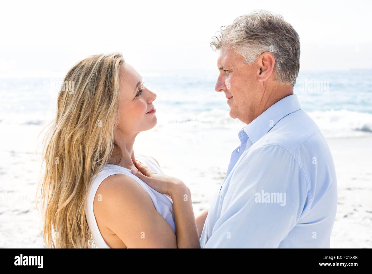 Happy couple standing by the sea and smiling at each other Stock Photo ...