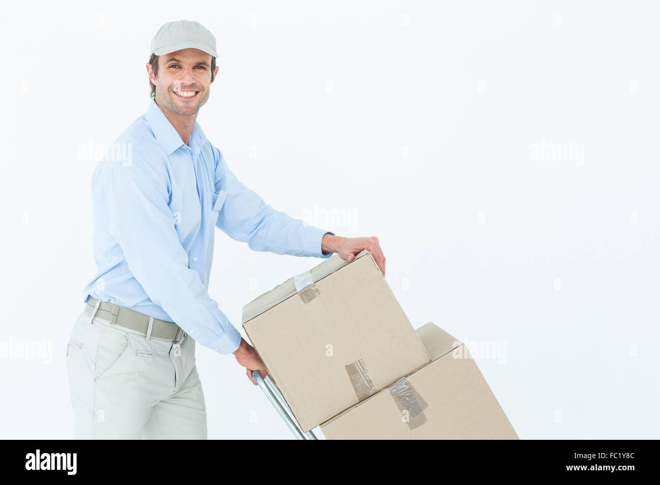 Confident delivery man pushing trolley of cardboard boxes Stock Photo