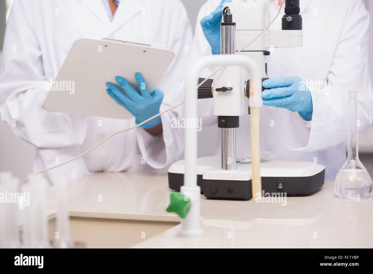 Scientists working with microscope and taking notes Stock Photo - Alamy