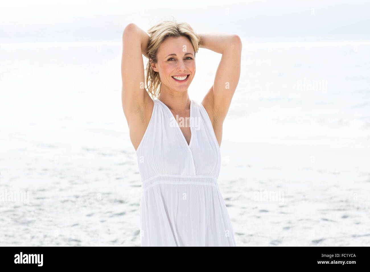Smiling blonde in white dress looking at camera Stock Photo - Alamy