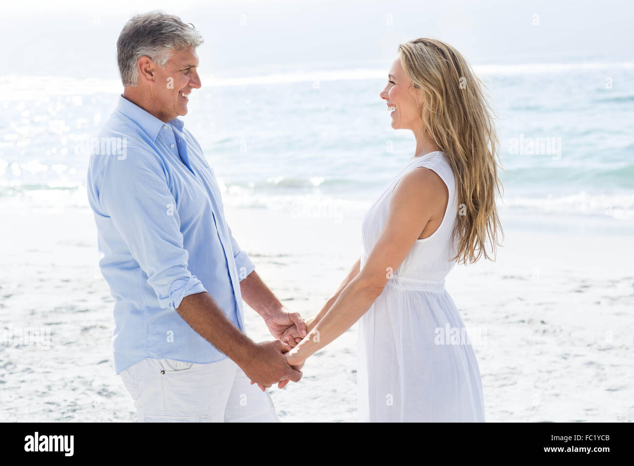 Happy couple holding hands and smiling at each other Stock Photo - Alamy