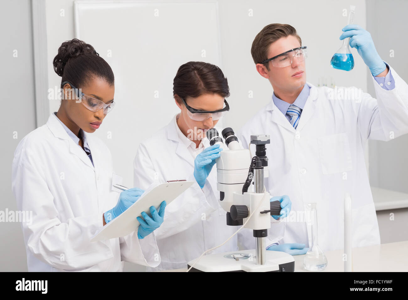 Scientists working attentively with microscope and beaker Stock Photo ...