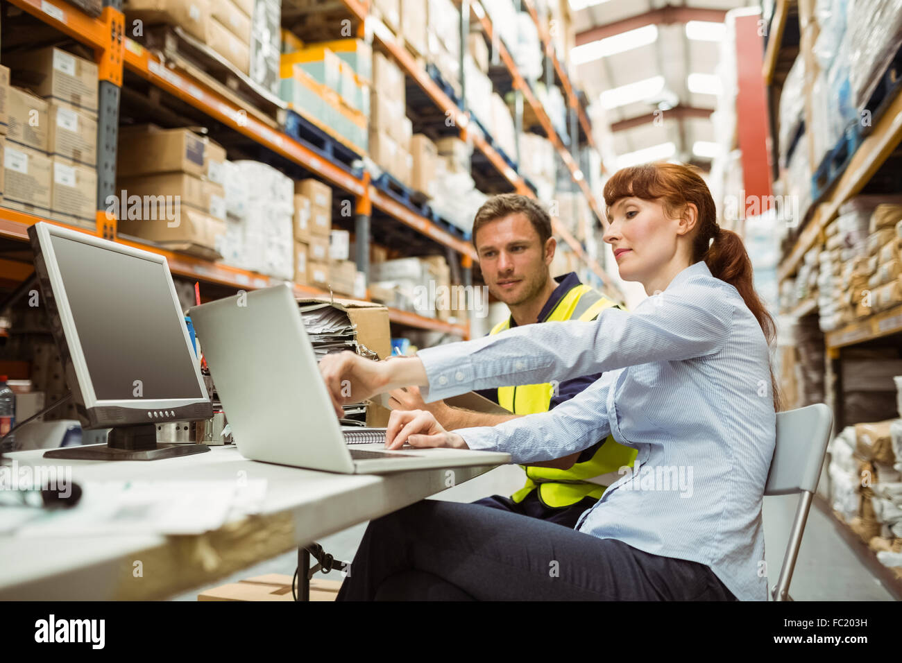 Warehouse worker and manager looking at laptop Stock Photo