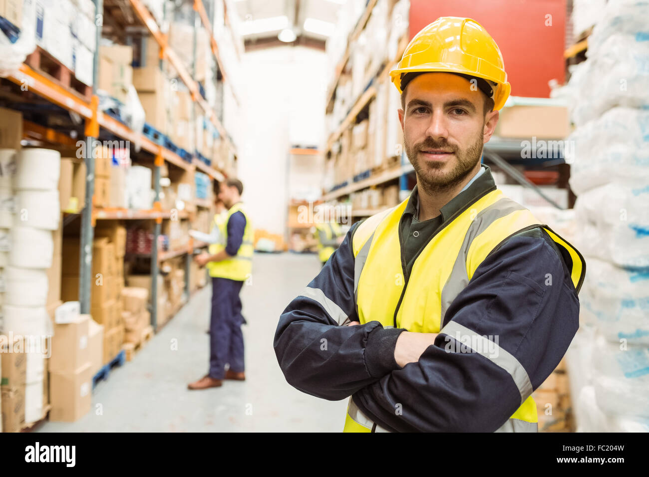 Smiling worker wearing yellow vest with arms crossed Stock Photo