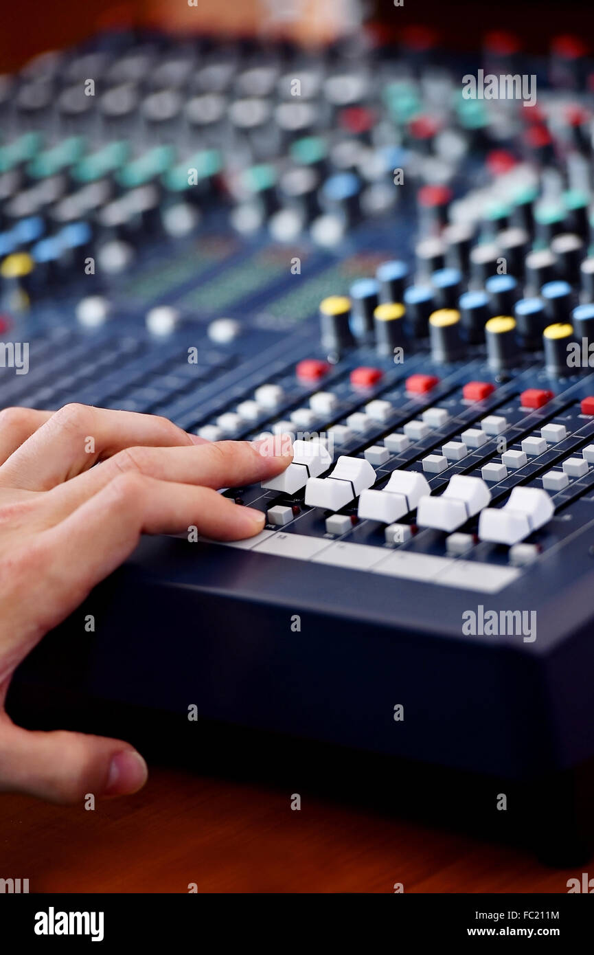 Detail with a hand adjusting sound levels on a professional audio mixer Stock Photo